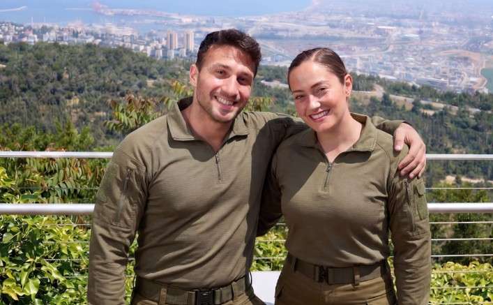 חיילת וחייל עומדים על רקע העיר חיפה